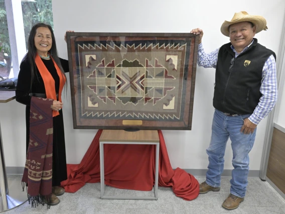 Joseph Bahe and Alberta Arviso pose next to a traditional Navajo rug woven and dyed by Bahe’s mother Frances Bahe, during the grand opening of the VetMed Den for Student Success. (Photo by College of Veterinary Medicine/Ted S. Warren)